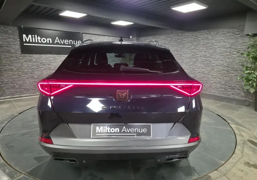 Vue arrière d'une CUPRA Formentor bleu pétrole 2023 avec hayon électrique et bandeau LED arrière lumineux.