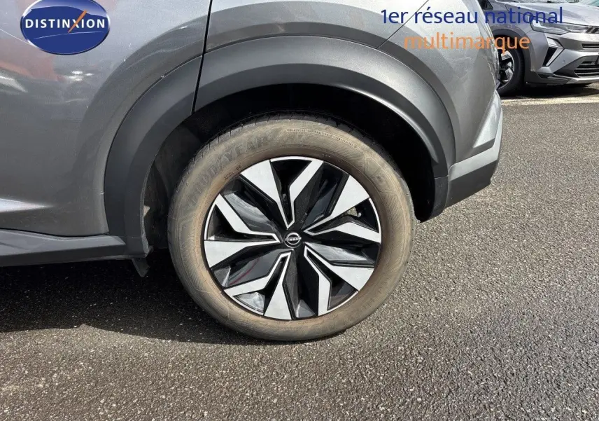 Gros plan sur la roue avant droite du Nissan Juke Hybrid 2025 en gris squale métal avec jante noire et argentée.