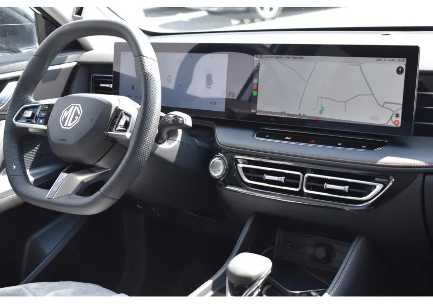 Intérieur du MG Motor EHS 1.5 Hybrid+ 224 ch Luxury 2026, vue du tableau de bord avec écran large et volant multifonction noir.