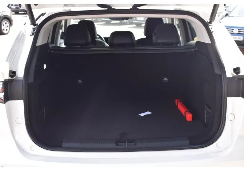 Coffre ouvert vu de l'arrière d'un MG MOTOR EHS blanc 2026, montrant un espace de chargement vide avec un triangle de sécurité rouge.