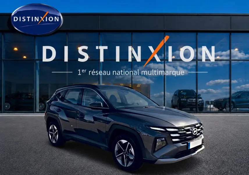 Hyundai Tucson gris ecotonic en 3/4 avant droit devant une vitrine avec logo Distinxion.