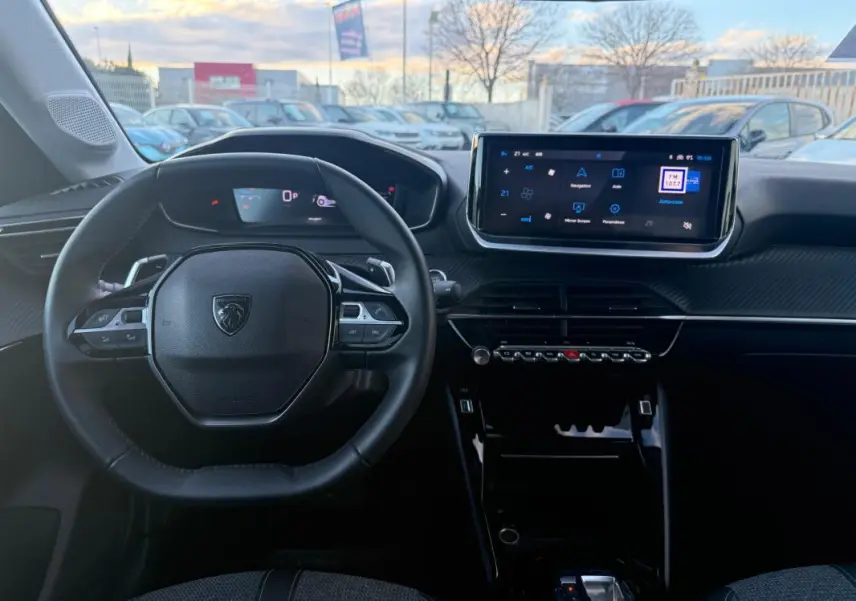 Vue intérieure frontale du poste de conduite noir de la Peugeot 208 Hybrid 110 e-DCS6 Allure avec écran tactile et volant multifonction.
