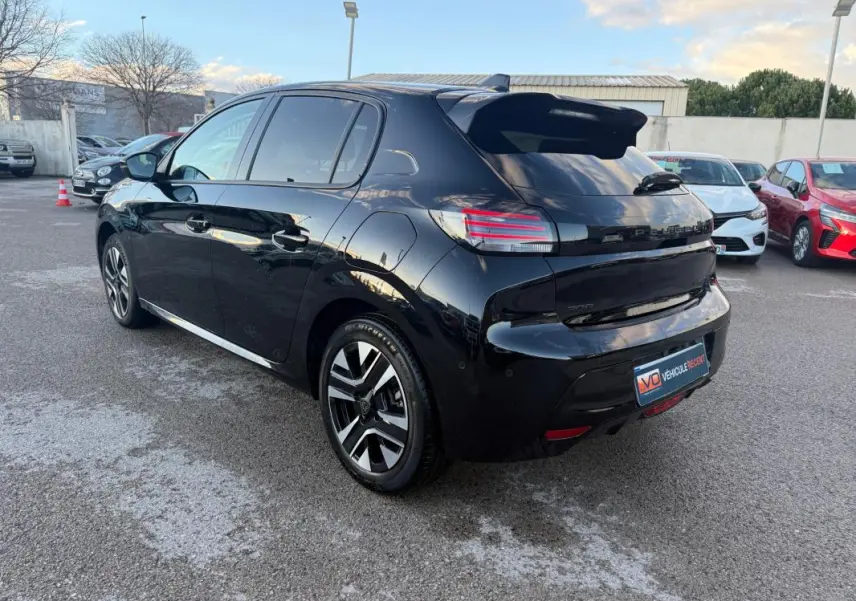 Vue 3/4 arrière droite d'une Peugeot 208 Hybrid 110 noire avec jantes alliage 16 pouces et antenne requin.