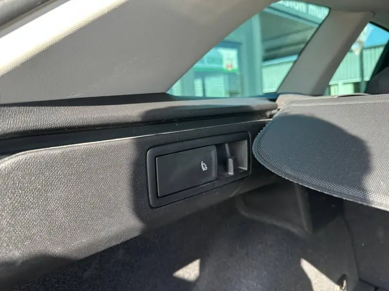 Détail intérieur du coffre côté gauche du SEAT LEON ST 2025 gris métallisé, montrant un bouton de rabattement de siège.