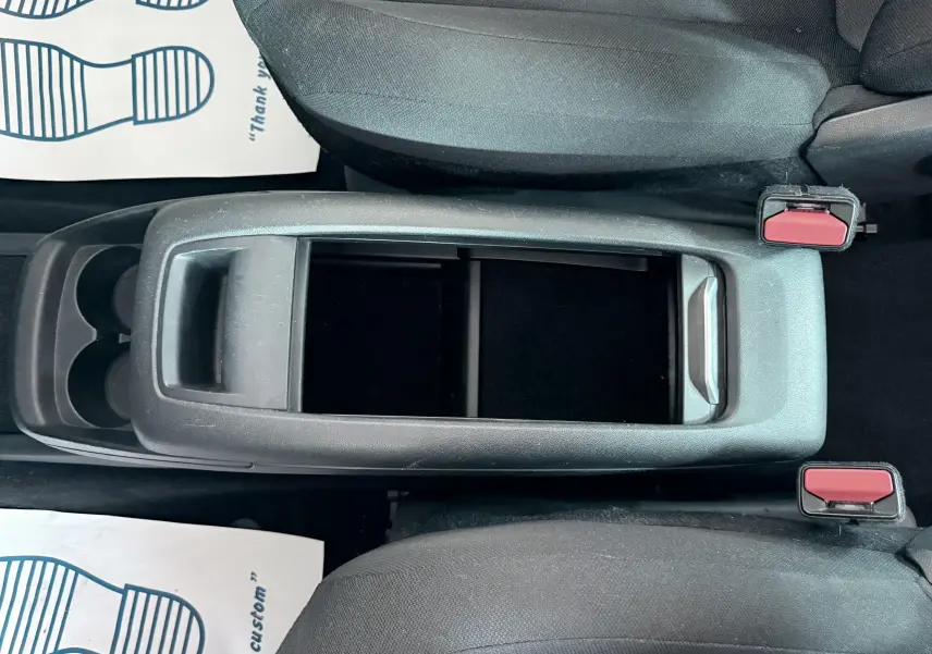 Vue plongeante sur la console centrale noire entre les sièges avant en tissu gris foncé du Citroën C4 Spacetourer.