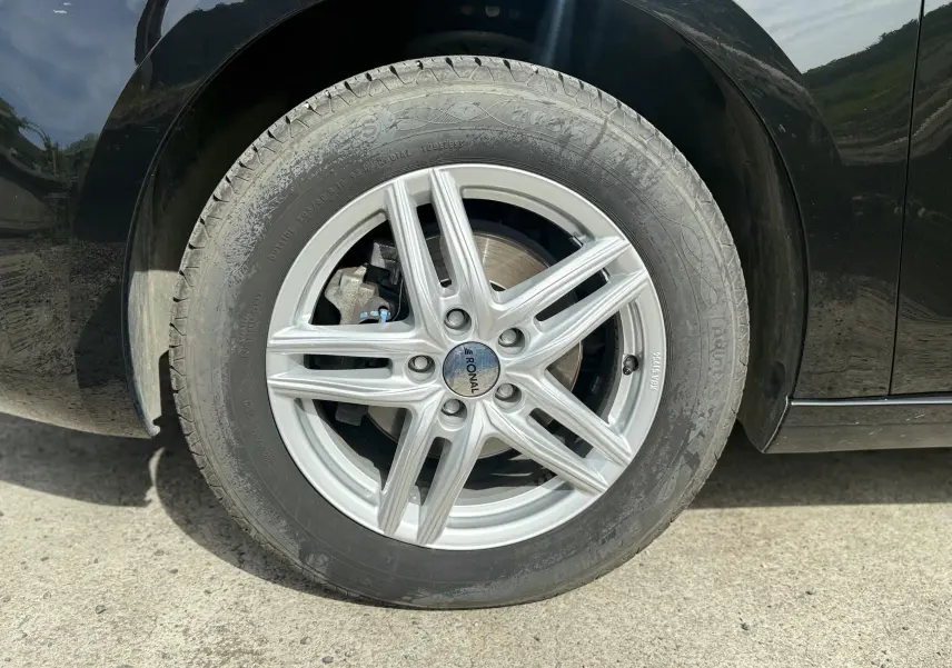 Gros plan sur la roue avant gauche noire d'une Citroën C4 Spacetourer avec jante alliage argent Ronal.