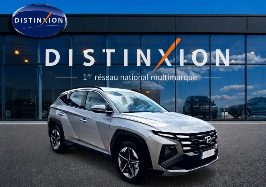 Hyundai Tucson gris shimmering en 3/4 avant droit, avec calandre distinctive et jantes alu 18 pouces.