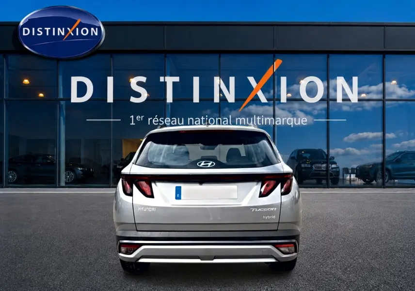 Vue arrière d'un Hyundai Tucson gris shimmering hybride garé devant une vitrine avec logo Distinxion.