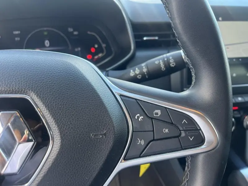 Gros plan sur le volant noir de la Renault Clio gris Titanium 2021, avec commandes audio intégrées et tableau de bord en arrière-plan.