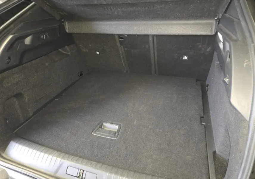 Coffre ouvert du Peugeot 3008 noir hybride 2025, vue intérieure montrant le plancher plat et les parois noires.