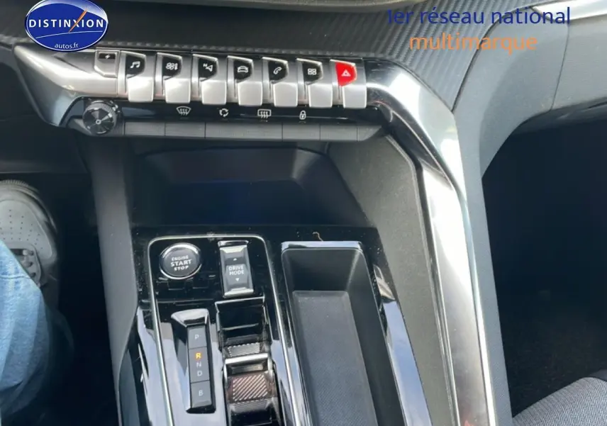 Vue intérieure centrée sur la console centrale noire brillante du Peugeot 3008 hybride 2024 avec commandes et levier de vitesses automatique.