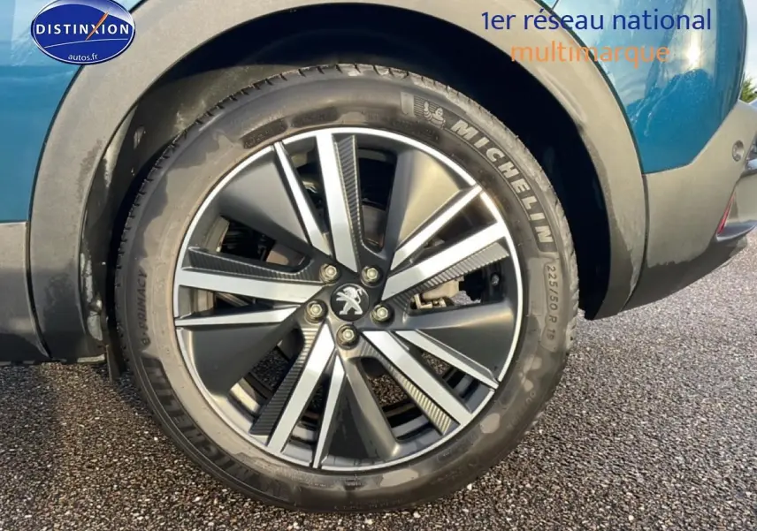 Gros plan sur la roue avant droite avec jante alu bicolore du Peugeot 3008 bleu 2024 plug-in hybrid.