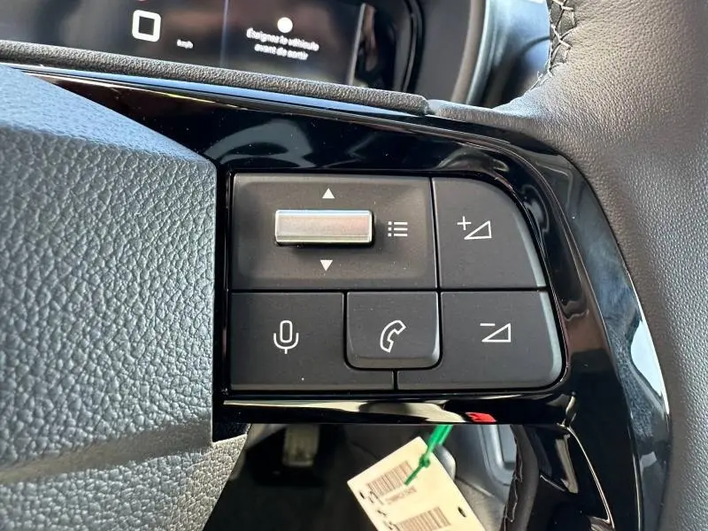 Gros plan sur les commandes noires du volant multifonction côté gauche du Citroën Berlingo blanc, avec touches de volume et appel.