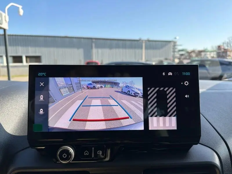Écran tactile intérieur montrant la caméra de recul du Citroën Berlingo blanc en vue arrière avec lignes de guidage colorées.