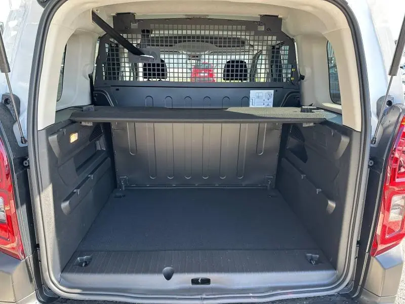 Coffre ouvert vu de l'arrière du Citroën Berlingo blanc avec cloison de séparation et tablette de rangement.