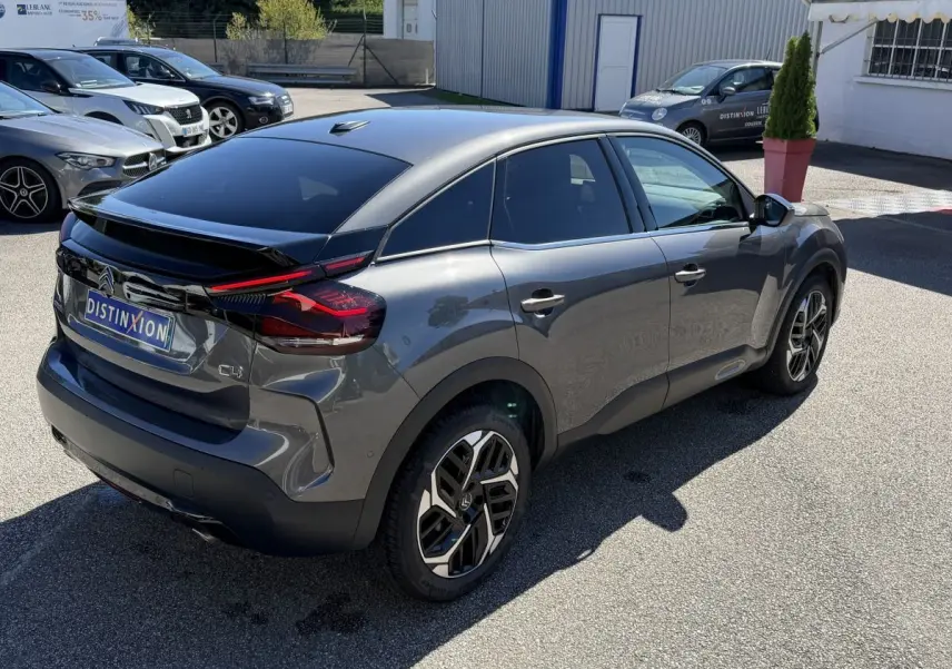 Vue 3/4 arrière droite d'une Citroën C4 PureTech 130 S&S Shine gris foncé avec feux arrière LED et jantes distinctives.