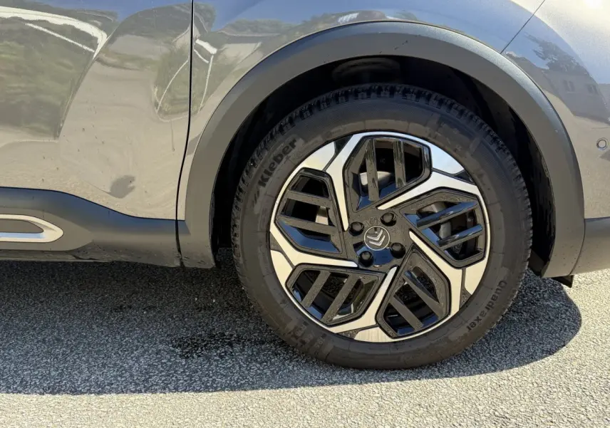 Gros plan sur la roue avant droite d'une Citroën C4 gris foncé, mettant en valeur la jante au design moderne bicolore.