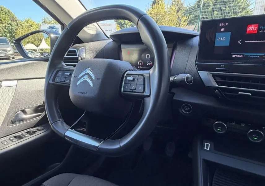 Vue intérieure centrée sur le volant cuir et tableau de bord digital de la Citroën C4 PureTech 130 S&S Shine 2022.