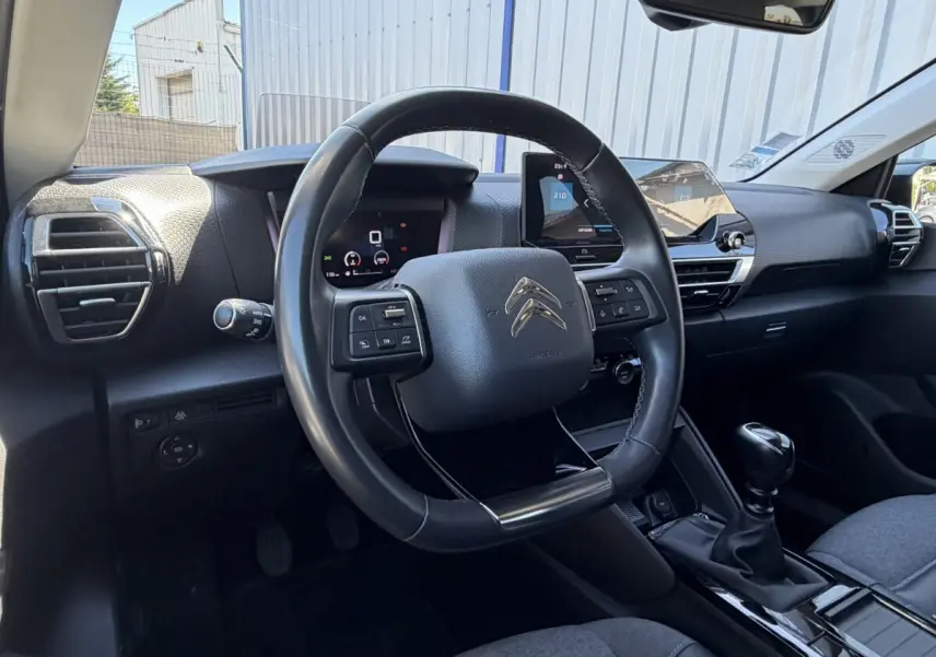Vue intérieure centrée sur le volant cuir multifonctions et le tableau de bord numérique de la Citroën C4 2022.