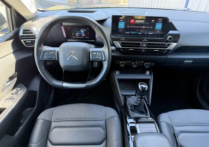 Vue intérieure avant centrée sur le volant cuir et tableau de bord numérique de la Citroën C4 PureTech 130 S&S Shine 2022.