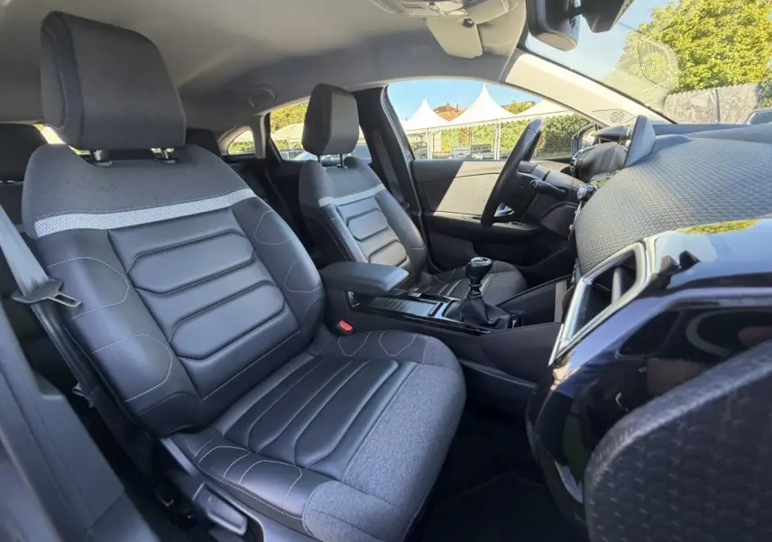 Vue intérieure côté conducteur de la Citroën C4 2022, sièges bi-matière gris et tableau de bord moderne.