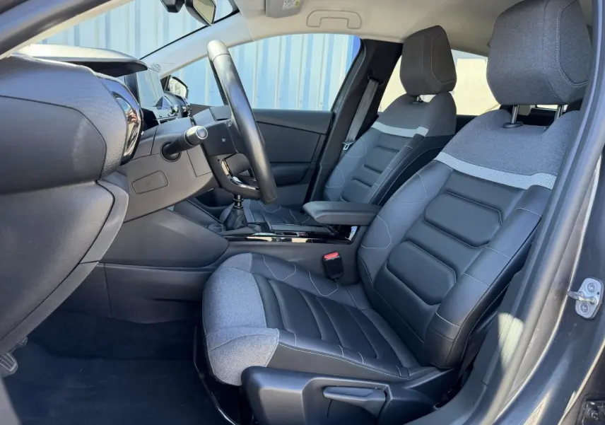 Vue intérieure côté conducteur de la Citroën C4 PureTech 130 S&S Shine 2022, sièges cuir et tissu gris foncé.