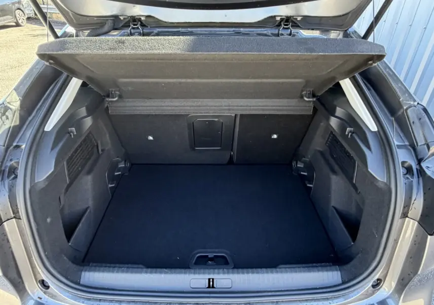 Coffre ouvert vu de l'arrière d'une Citroën C4 gris foncé, montrant un espace de chargement propre et spacieux.