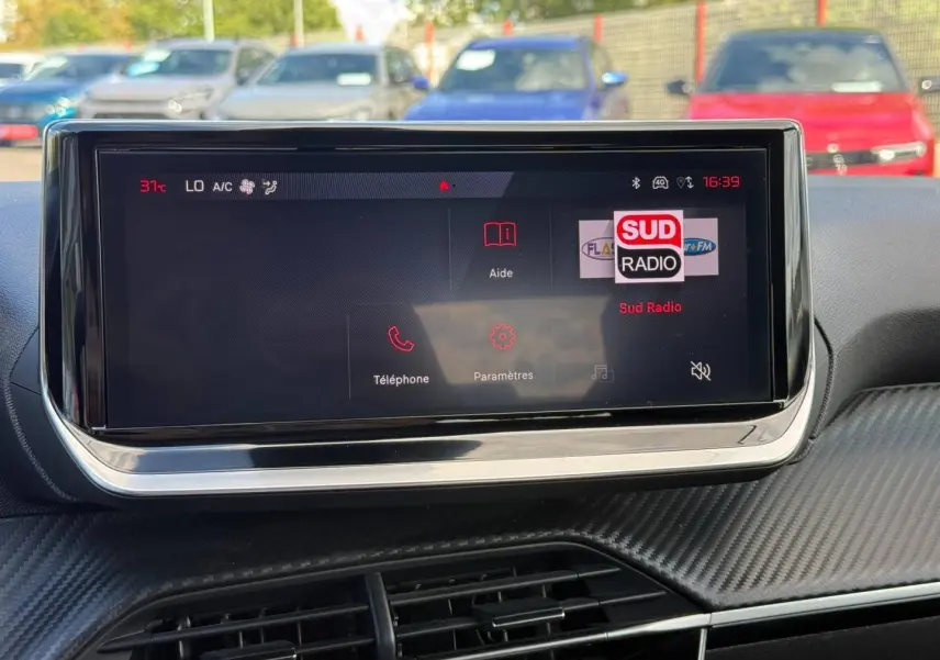 Écran tactile central de la Peugeot 208 1.2 100ch Allure, affichant la radio Sud Radio en extérieur lumineux.