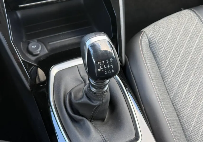 Le levier de vitesse manuel noir de la Peugeot 208 1.2 100ch Allure avec sellerie tissu gris et surpiqûres contrastées.