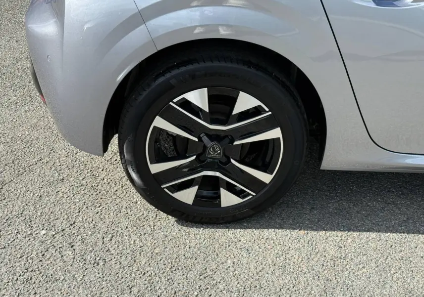 Gros plan sur la roue arrière droite de la Peugeot 208 gris Artense avec jante alu au design moderne.