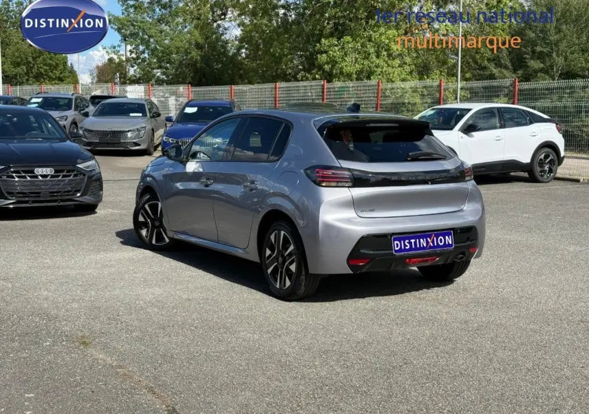 Vue 3/4 arrière droite d'une Peugeot 208 gris Artense avec jantes alliage, sur un parking extérieur ensoleillé.