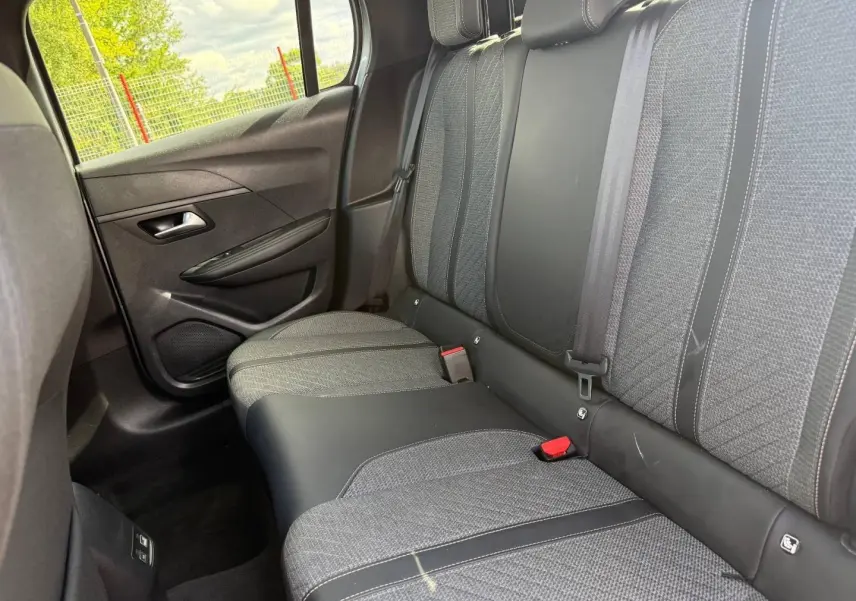 Vue intérieure côté gauche sur la banquette arrière tissu gris et cuir noir de la Peugeot 208 1.2 100ch Allure 2025.