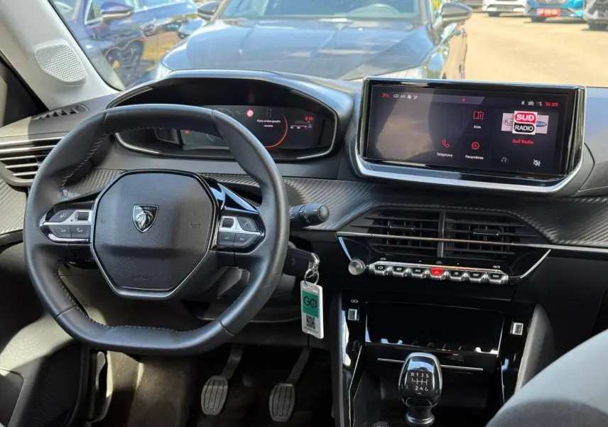 Vue intérieure du tableau de bord et volant de la Peugeot 208 gris Artense avec écran tactile et boîte manuelle.