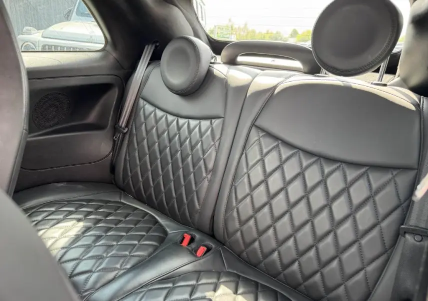 Vue rapprochée des sièges arrière en cuir noir matelassé de l'Abarth 500 blanc, avec appuie-têtes ronds.