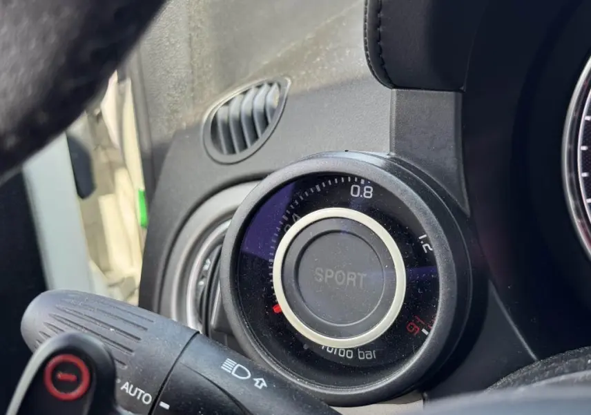 Gros plan sur le manomètre de pression turbo avec mode Sport dans l'habitacle de l'Abarth 500 blanc.