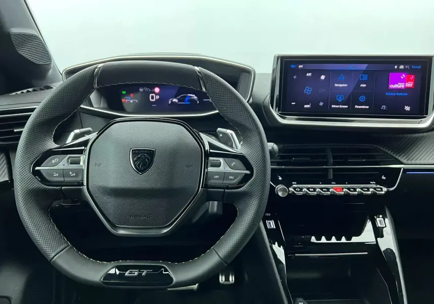 Intérieur noir du Peugeot 208 1.2 HYBRID 136 GT 2025, vue centrée sur le volant compact et l’écran tactile moderne.