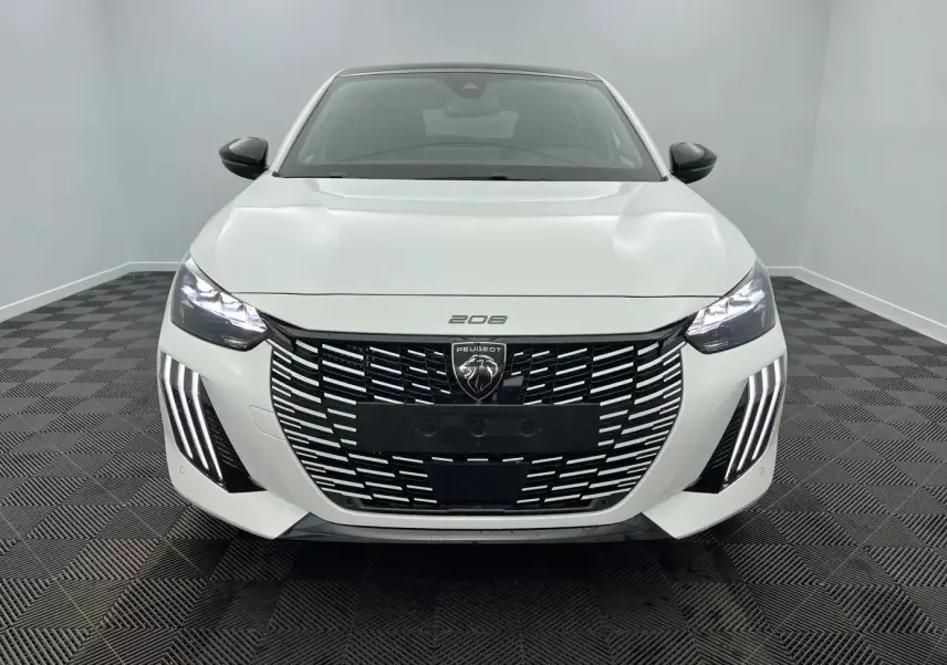 Peugeot 208 1.2 Hybrid 136 GT blanc vue de face, avec calandre large et feux LED distinctifs allumés.