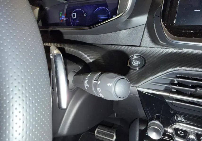 Gros plan sur la commande d’essuie-glace et bouton start du tableau de bord noir à effet carbone de la Peugeot 208 1.2 Hybrid 136 GT.