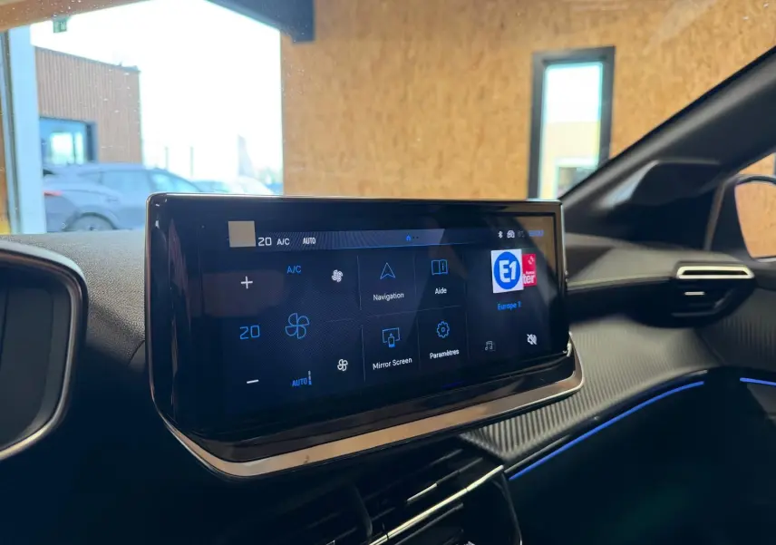 Écran tactile central du tableau de bord intérieur de la Peugeot 208 1.2 Hybrid 136 GT, ambiance noire avec éclairage bleu.