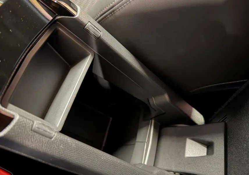 Gros plan sur le rangement central ouvert de l’intérieur noir en tissu du Peugeot 208 1.2 Hybrid 136 GT.