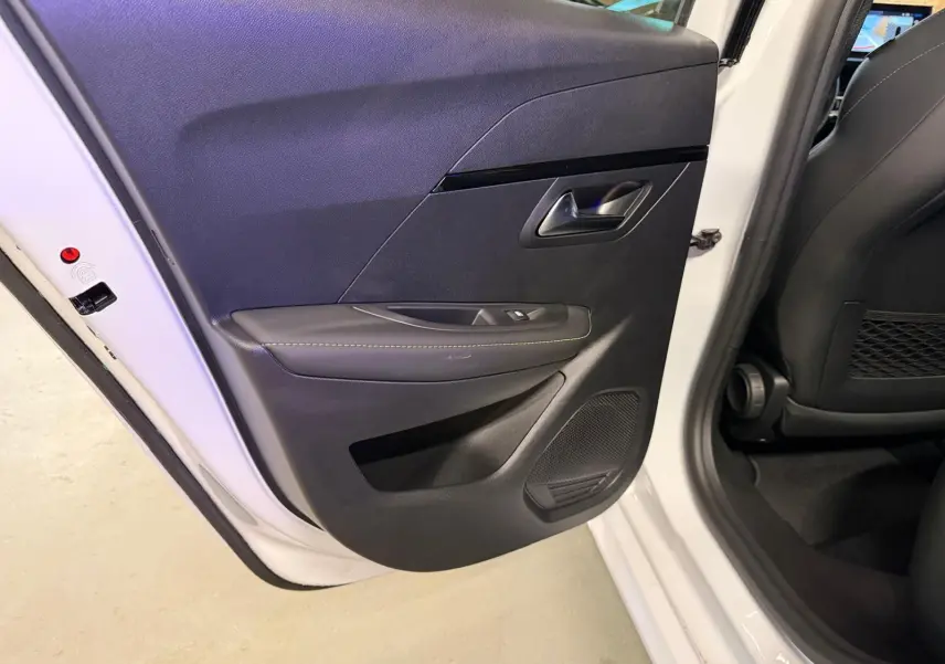 Vue intérieure de la porte arrière gauche noire avec surpiqûres vertes sur une Peugeot 208 blanche 1.2 Hybrid 136 GT 2025.