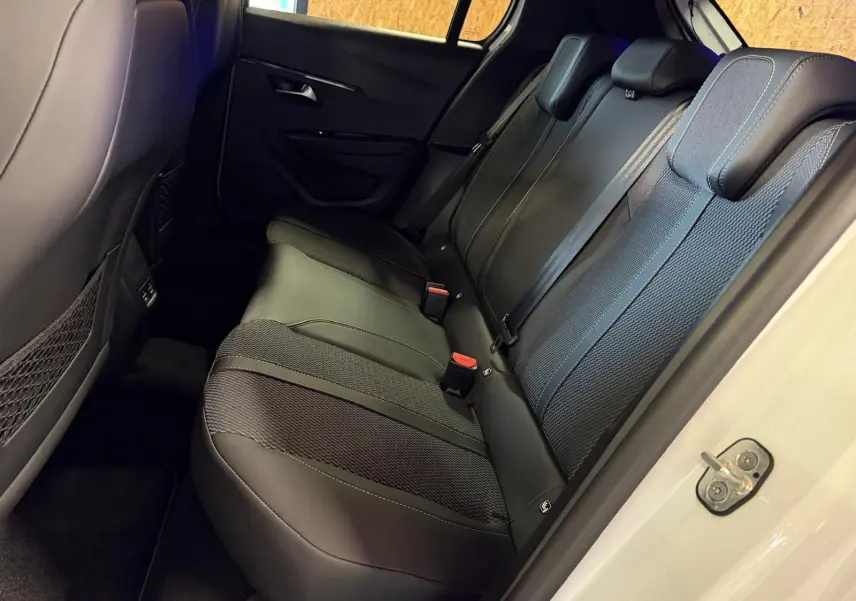 Vue intérieure côté droit des sièges arrière noirs en tissu et cuir de la Peugeot 208 1.2 HYBRID 136 GT blanche 2025.