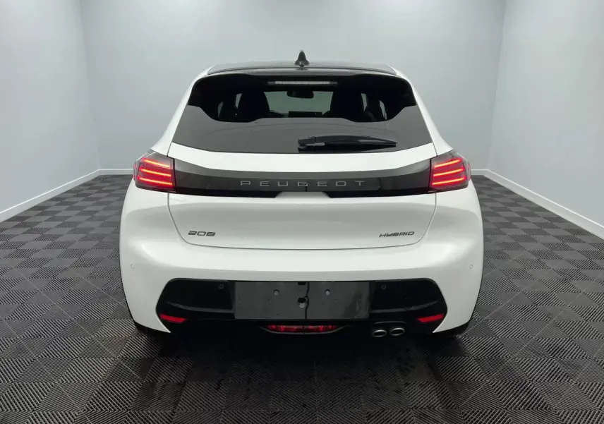 Vue arrière d'une Peugeot 208 blanche hybride 2025 avec feux arrière allumés et double sortie d'échappement côté droit.