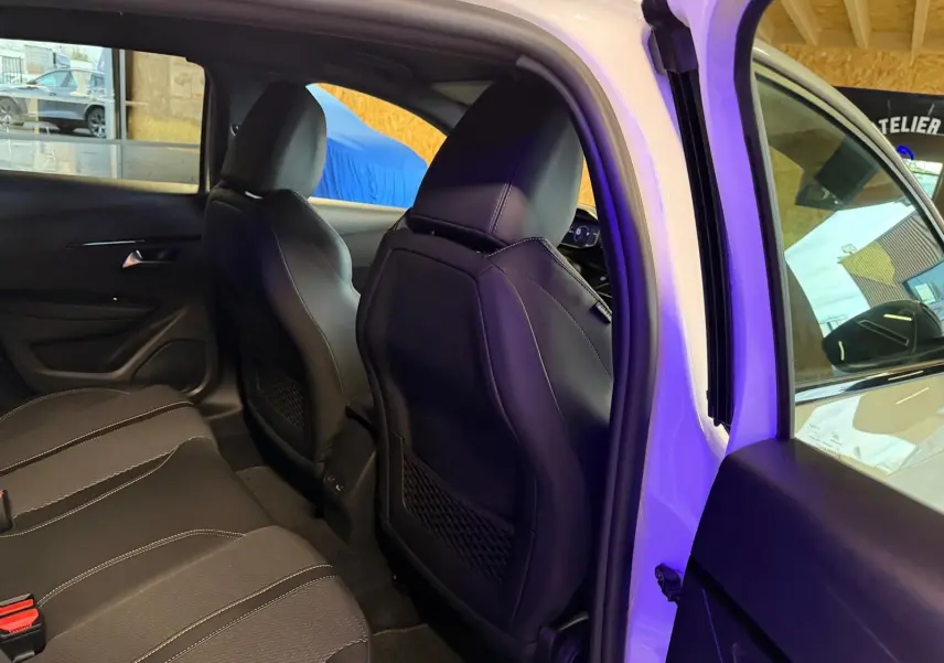 Vue intérieure arrière côté droit de la Peugeot 208 1.2 HYBRID 136 GT blanche, sièges noirs en tissu et cuir.