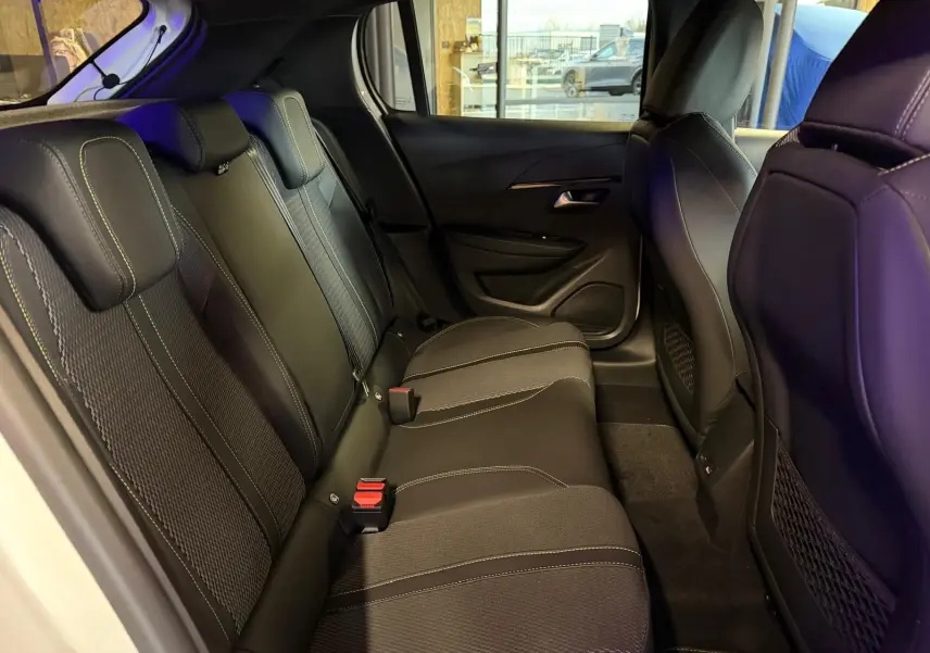 Vue intérieure côté gauche des sièges arrière en tissu noir avec surpiqûres claires d'une Peugeot 208 1.2 Hybrid 136 GT blanche.