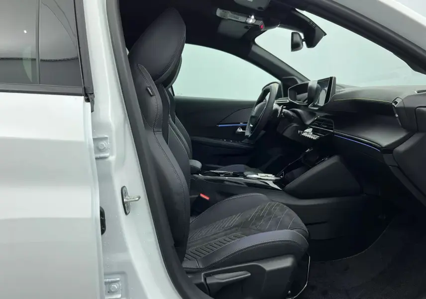 Vue intérieure côté conducteur d'une Peugeot 208 1.2 Hybrid 136 GT blanche, sièges noirs en tissu et tableau de bord moderne.