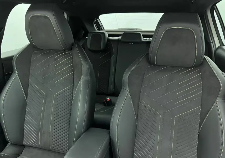 Gros plan sur les sièges avant noirs en tissu et alcantara avec surpiqûres jaunes dans l’habitacle d’une Peugeot 208 1.2 Hybrid 136 GT.