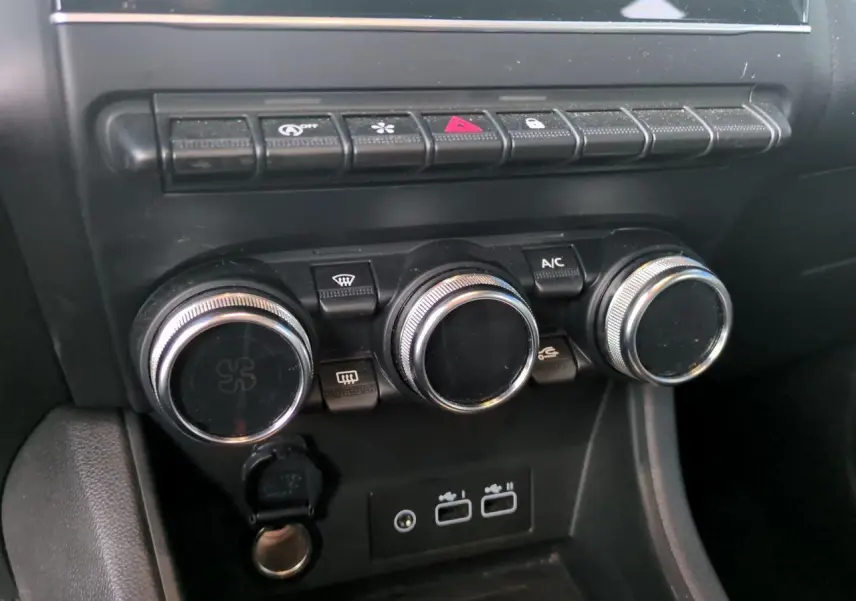 Gros plan sur la console centrale noire du Renault Captur 2024, avec commandes de climatisation et prises USB visibles.