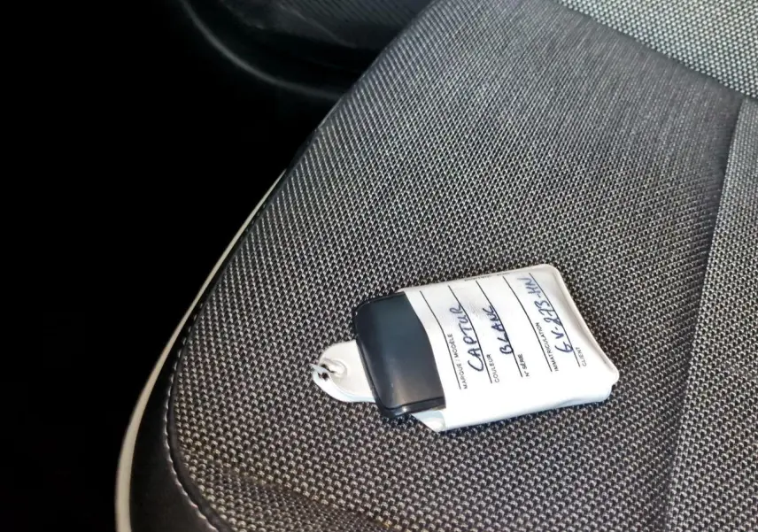 Gros plan sur la clé avec étiquette blanche posée sur le siège tissu gris foncé côté conducteur du Renault Captur blanc.