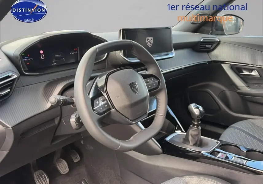 Vue intérieure avant gauche du Peugeot 2008 1.2 100 allure 2025, volant multifonction et levier de vitesse manuel visibles.